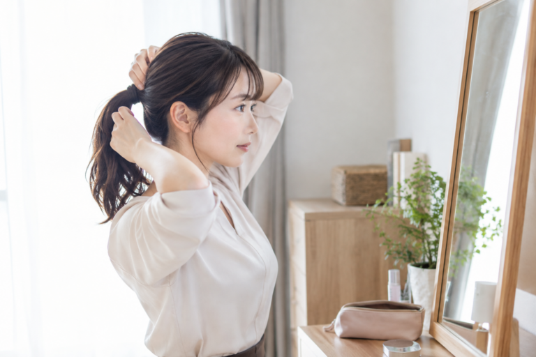 鏡の前で髪を結び直す女性