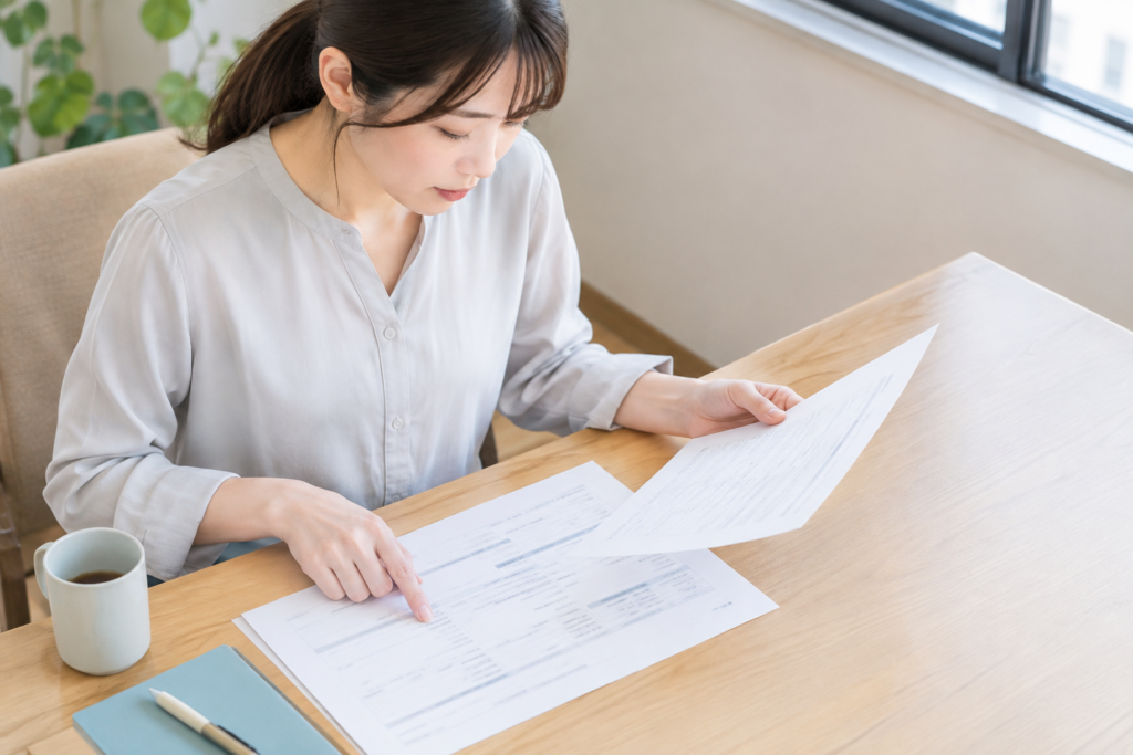 机に向かって書類を見比べる女性