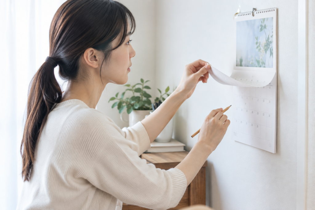 女性が壁のカレンダーを見ながら予定を確認している