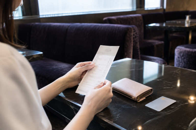 店内のテーブルで女性が紙の明細を確認している