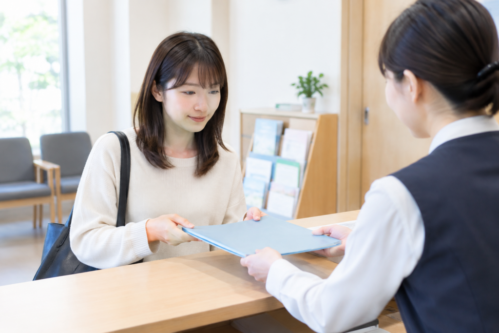 女性がカウンター越しに書類を受け取り、相談員と面談している様子