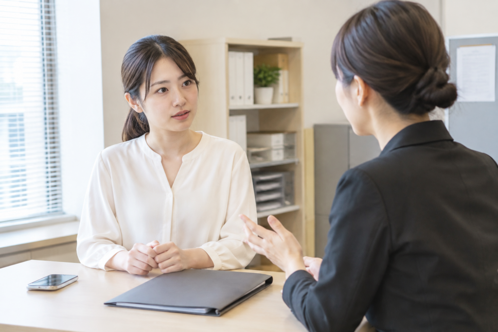 机を挟んで女性同士が面談している様子